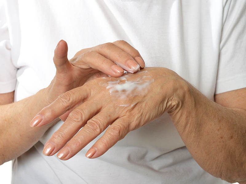 Close-up view of woman applying cream to hands