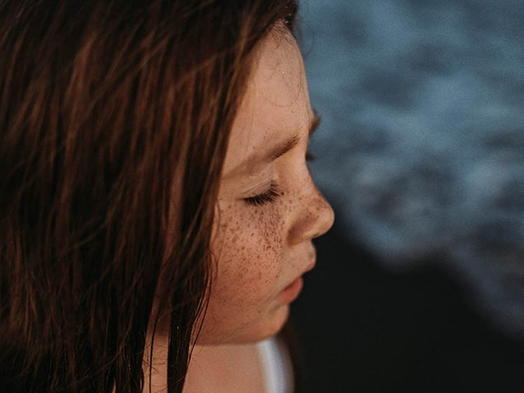 Young girl with multiple freckles on her cheek and nose.