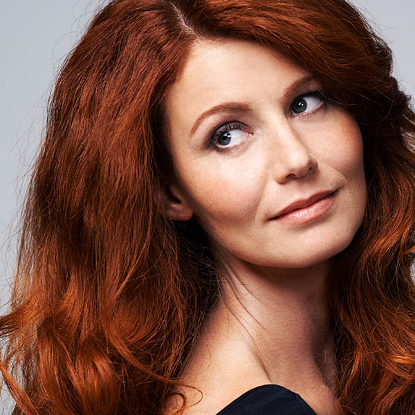 Woman with long auburn hair and fair skin, looking back over her shoulder, representing BBL treatment