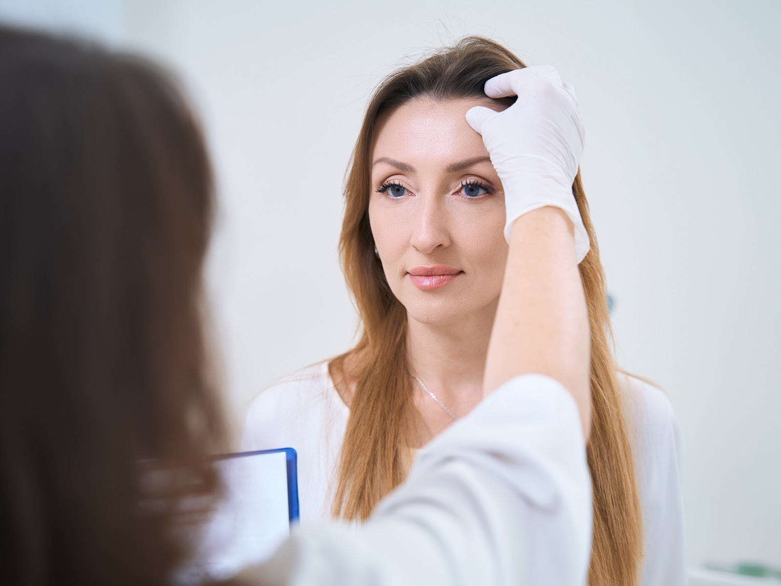 A nurse examines a woman's face for a cosmetic skin treatment